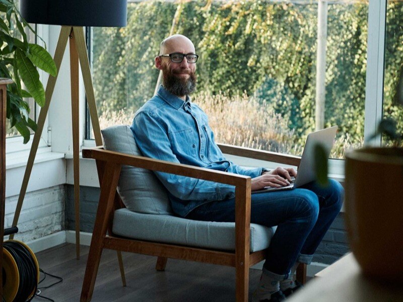 Mand i lænestol med computer
